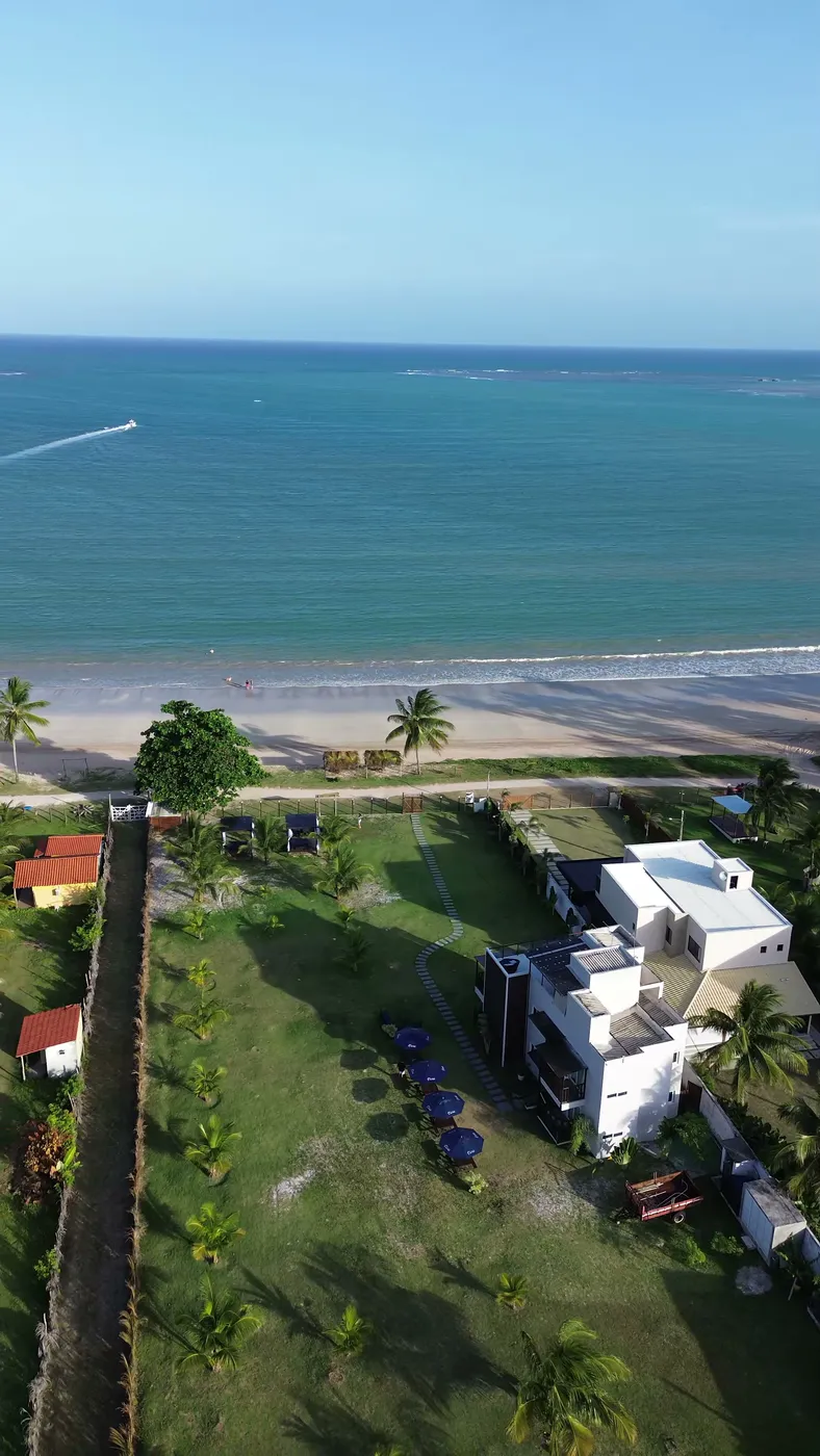 Vista aérea do Brisas do Mar Flats: o prédio branco, o gramado com caminho de pedras e a Praia de Garapuá logo à frente