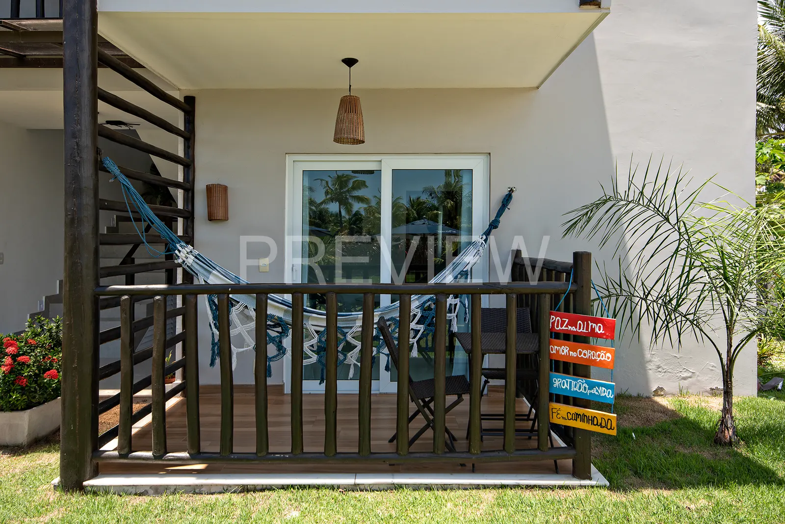 Varanda térrea do flat de 1 quarto com rede azul e mesa de frente para o jardim