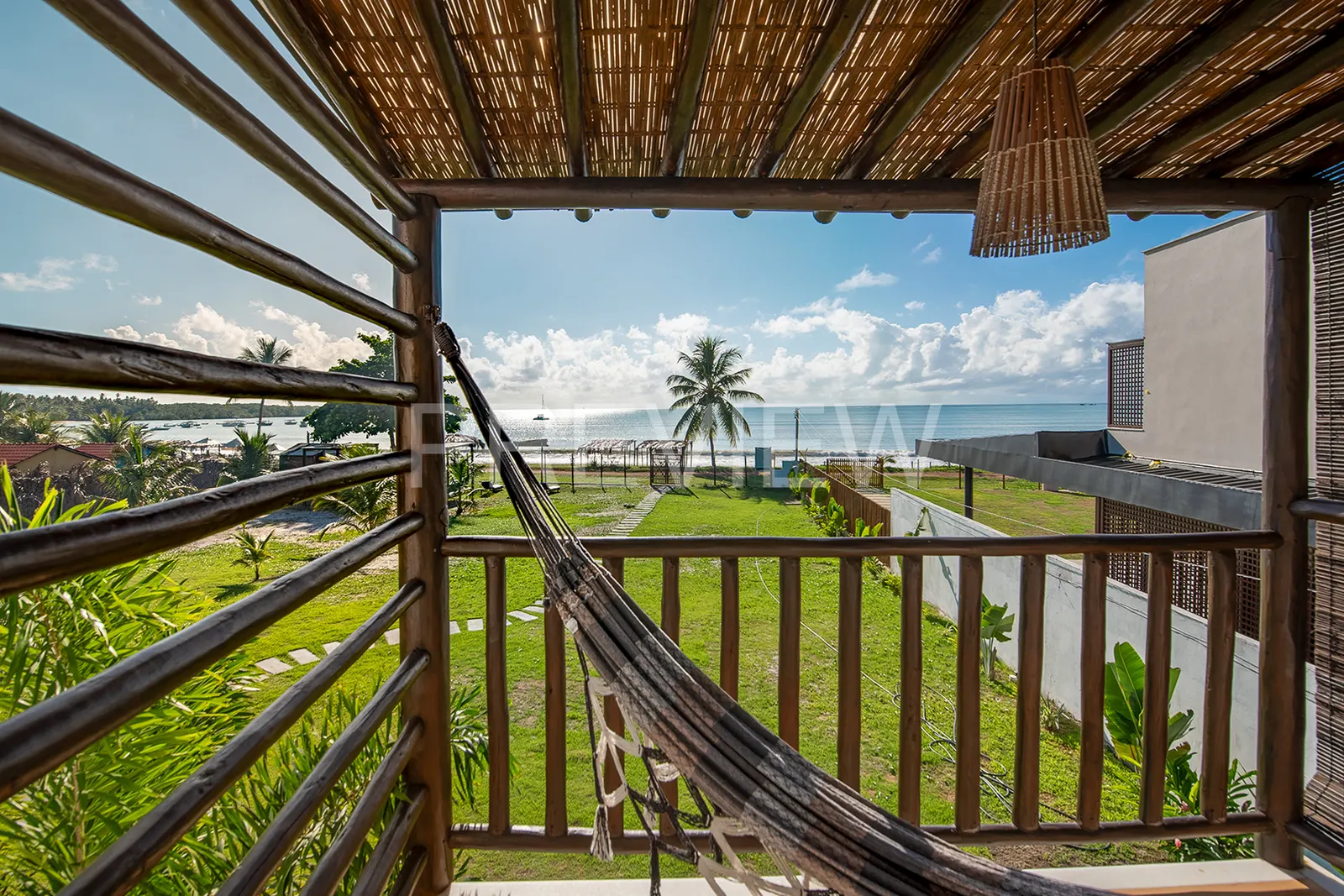 Varanda com pergolado e rede do flat de 2 quartos, com vista panorâmica do mar de Garapuá
